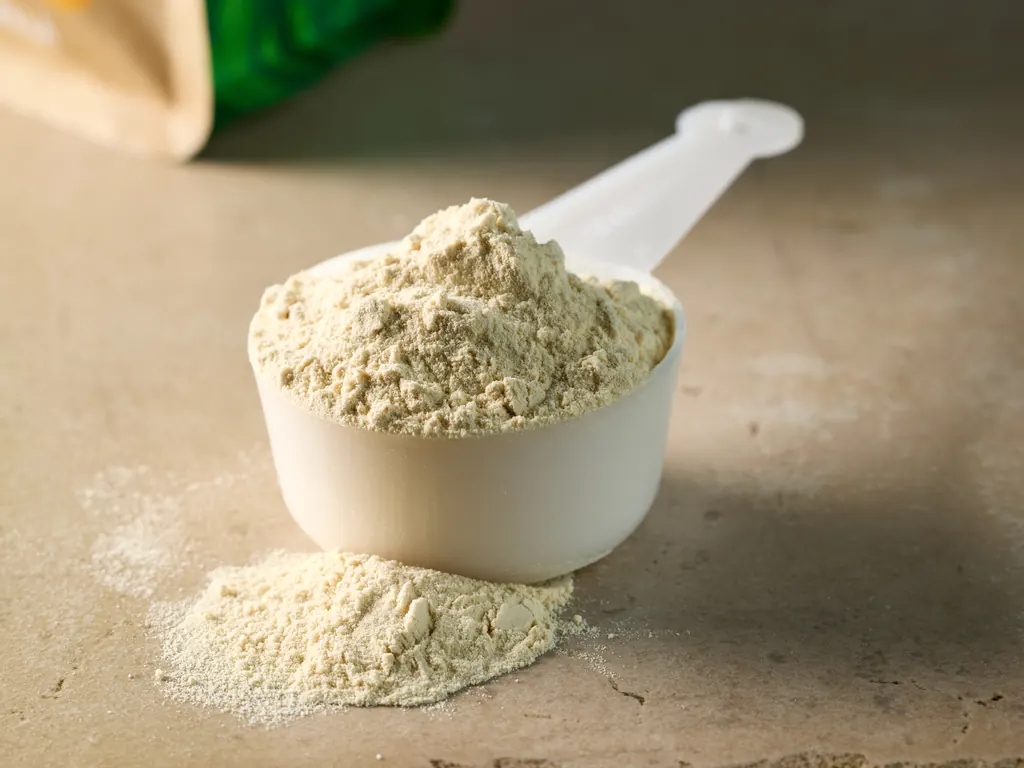 A heaped scoop of fine pea protein powder on a stone surface